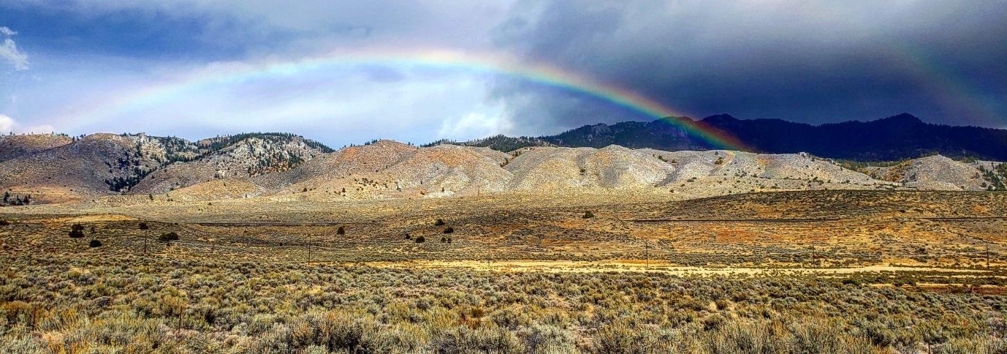 A rainbow and clouds over scrubland land