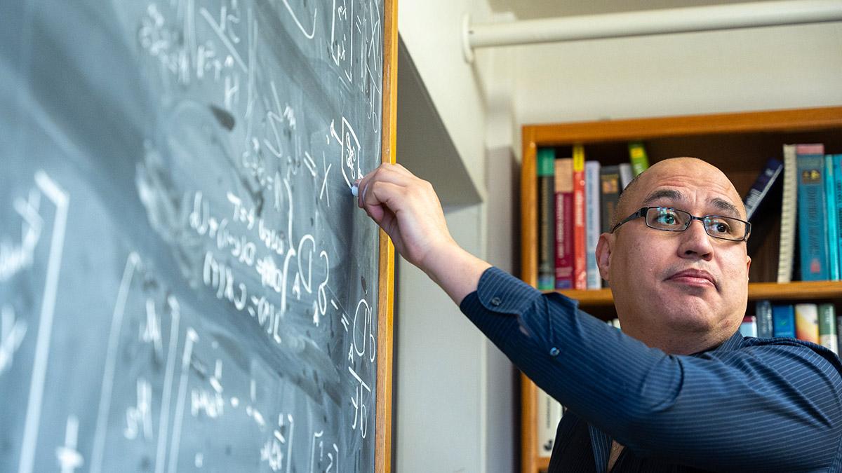 A professor writing on a chalk board