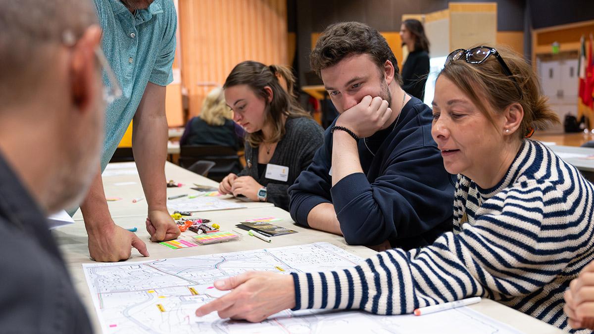 A group of people talking with a girl pointing to a piece of paper